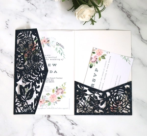 Detail of navy blue glitter laser cut wedding invitation with floral insert and RSVP card