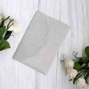 Silver glitter cardstock for elegant wedding invitations on a white wooden background
