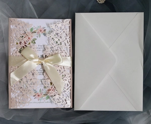 Pink laser-cut leaf pattern invitation card with ribbon bow and floral envelope