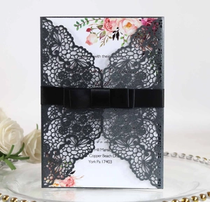 Detailed laser-cut wedding invitation with black lace design and pink floral inner card