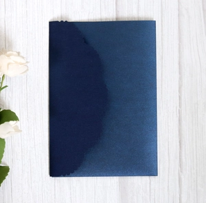 Macro detail of laser-cut wavy edge on premium navy blue pearlescent paper card
