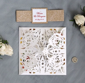 Detail showing laser-cut wedding invitation with gold glitter band and floral envelope