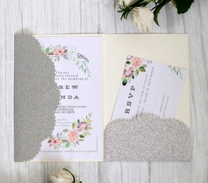 Elegant silver glitter laser cut wedding invitation set with floral card on wood background
