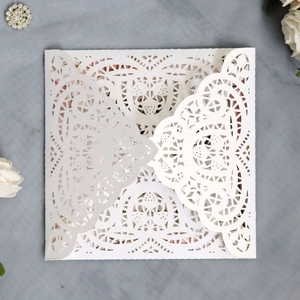 Close-up of laser-cut wedding invitation featuring heart and floral lace patterns