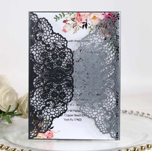 Detail of laser-cut black lace invitation sleeve with floral printed inner card