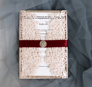 Pink laser-cut invitation card with floral patterns, glitter border, and silk ribbon