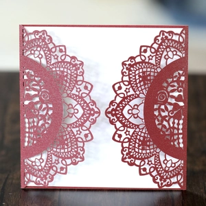 Macro detail of laser-cut burgundy invitation with intricate floral lace texture