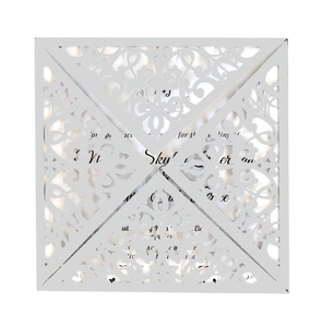 Detail of white laser-cut wedding invitation with intricate floral lace pattern