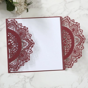 Macro view of burgundy laser-cut floral invitation cover with shimmering paper texture