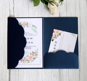 Navy blue laser-cut wedding invitation with elegant floral inner cards on wood background
