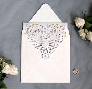 Detailed view of white laser-cut floral wedding invitation with elegant envelope and card