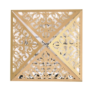 Detail of laser-cut gold wedding invitation with elegant floral scroll patterns and white insert