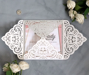 Elegant laser-cut lace wedding invitation with pink marble inner card on grey fabric