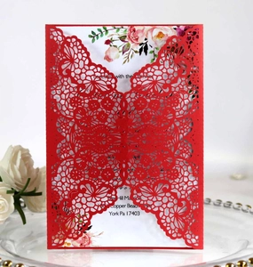 Close-up of laser-cut wedding invitation featuring red floral lace and white rose inner card