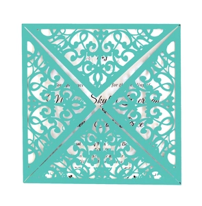 Detail of laser-cut turquoise invitation card featuring intricate floral vine patterns