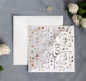 Detail of laser cut white lace wedding invitation with gold floral border inner card