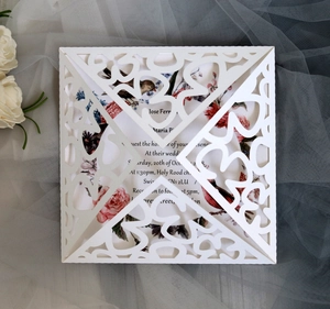 Detailed laser-cut white floral wedding invitation with bird motif and soft mesh background