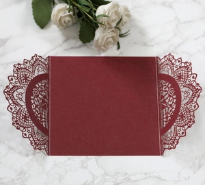Macro detail of laser-cut lace pattern on burgundy pearlescent paper invitation cover