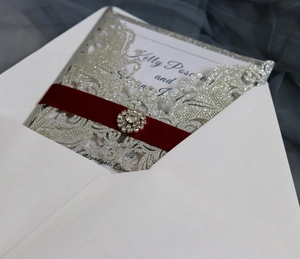 Macro di un invito a nozze glitterato argento con nastro rosso e fibbia in strass