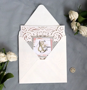 Detail of laser-cut lace wedding invitation with pink marble card and white floral envelope