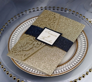 Macro detail of laser-cut wedding invitation with navy glitter band on gold sleeve