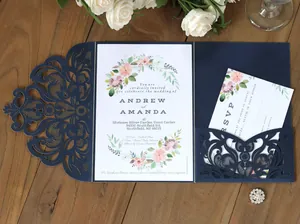 Detail of laser-cut navy blue floral invitation sleeve with pink floral cards on wood