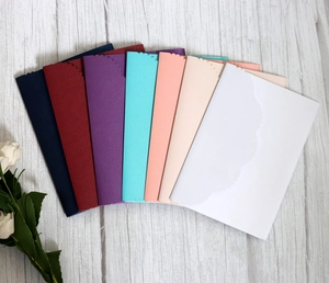 Laser-cut wavy edge wedding invitations in seven colors arranged in a fan shape