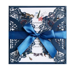 Detail of laser-cut navy blue wedding invitation cover with silk ribbon and floral inner card