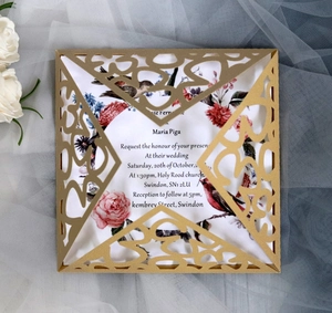 Detail of laser cut gold wedding invitation featuring vintage floral and bird patterns