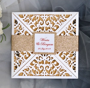 Macro detail of laser cut wedding invitation with gold glitter band and white lace cover