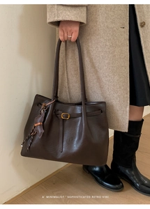 Close-up of retro dark brown tote bag with gold buckle and brown bear leather charm