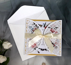 Elegant white laser-cut wedding invitation with cream ribbon bow and floral inner card