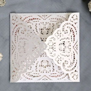 Elegant laser-cut white pearlescent paper wedding invitation with lace heart patterns