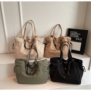 Dettaglio di quattro borse tote in nylon colorato con coulisse su scale bianche minimaliste