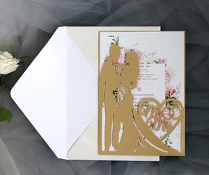 Detailed laser cut gold wedding invitation with floral insert and romantic silhouette