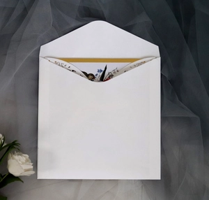Close-up of white lace cutout envelope with natural floral greeting card on soft grey tulle