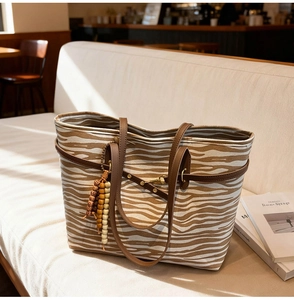 Close-up of zebra print tote bag with brown leather straps and wooden bead tassel