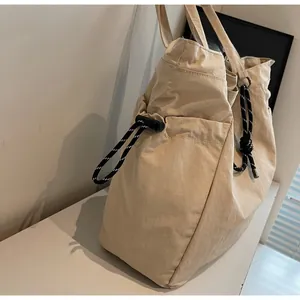Dettaglio di una borsa tote in nylon kaki con coulisse laterali e manici intrecciati