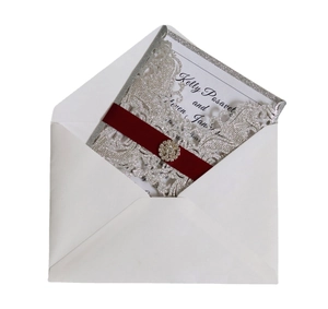 Invitation mariage argentée découpée au laser avec ruban bordeaux et boucle strass