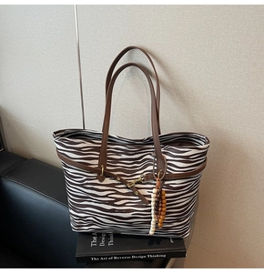Detail of zebra pattern tote bag with leather straps and colorful beaded charm