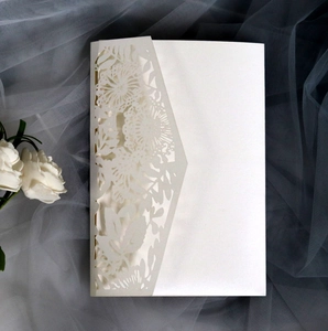 Detailed laser-cut white floral invitation card with pearlescent finish on soft tulle