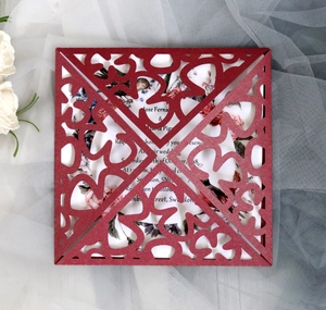 Macro detail of laser-cut burgundy invitation with intricate floral lace and glitter texture