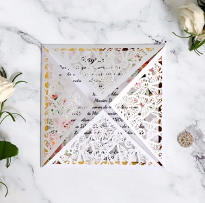 Detailed laser-cut wedding invitation with white butterfly motifs on marble background