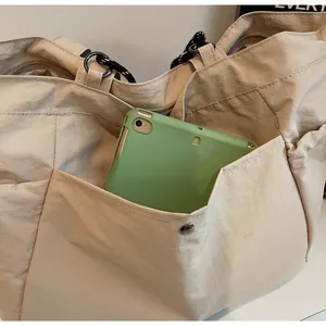 Dettaglio della borsa tote in tela beige con ampia tasca frontale per un tablet