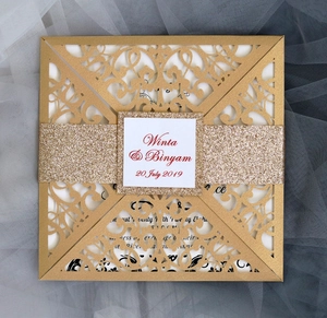 Macro detail of laser-cut wedding invitation with golden glitter band and lace pattern