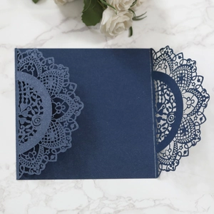 Macro detail of laser cut mandala patterns on navy blue pearlescent invitation card