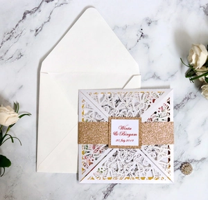 Detailed laser-cut wedding invitation featuring butterfly lace patterns and gold glitter band