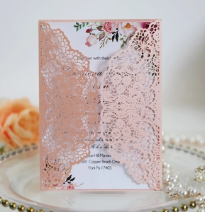 Detailed macro of laser-cut lace wedding invitation with floral printed inner card