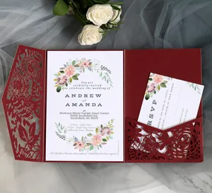 Detail of burgundy laser-cut lace wedding invitation with floral insert and RSVP cards
