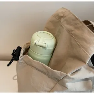 Dettaglio di una tasca laterale su una borsa tote kaki con una bottiglia d'acqua